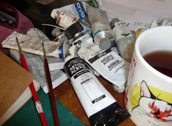 paints and brushes and a mug of tea